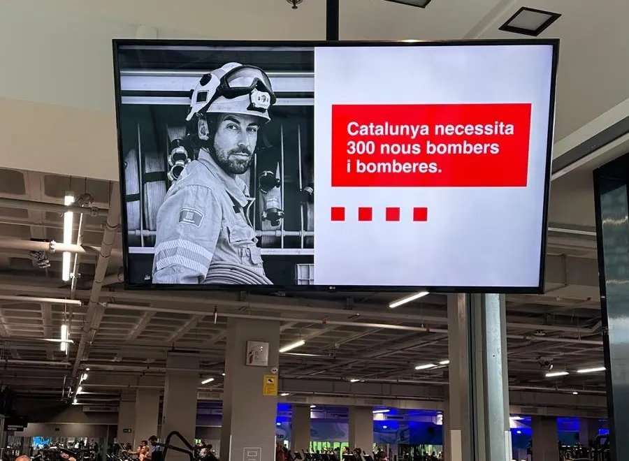 Pantalla de un gimnasio con un mensaje corto: Catalunya necesita 300 nous bombers